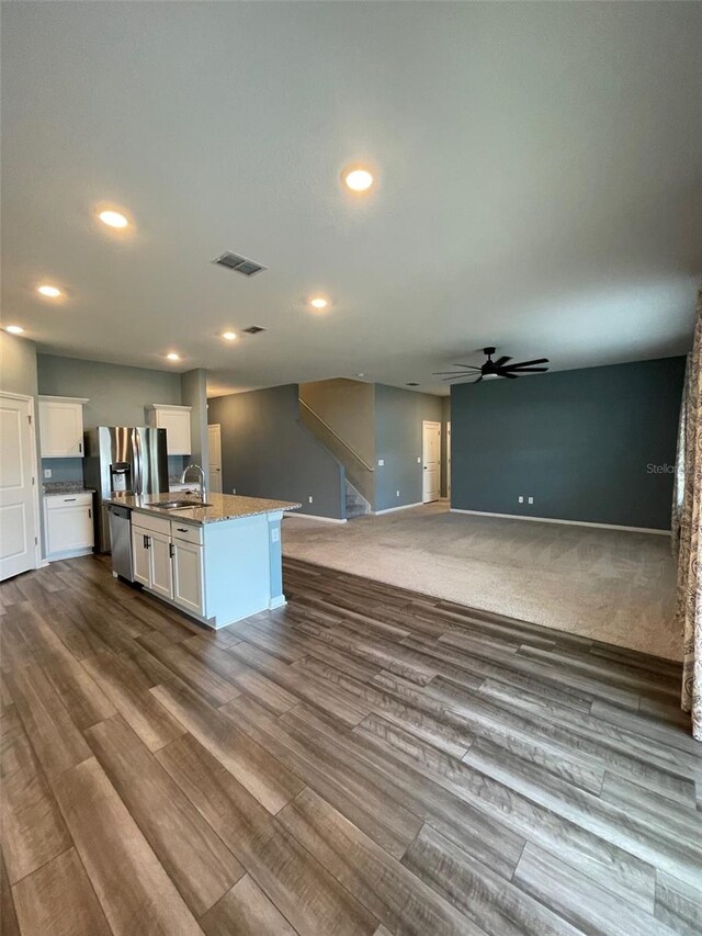 kitchen with hardwood / wood-style floors, white cabinetry, a kitchen island with sink, and sink