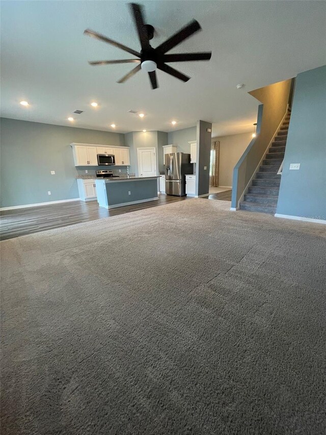 unfurnished living room featuring dark carpet and ceiling fan