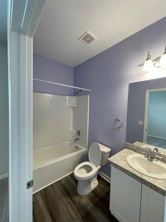 full bathroom with tub / shower combination, a textured ceiling, toilet, vanity, and hardwood / wood-style flooring