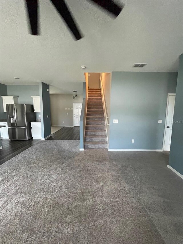 unfurnished living room featuring a textured ceiling and dark carpet