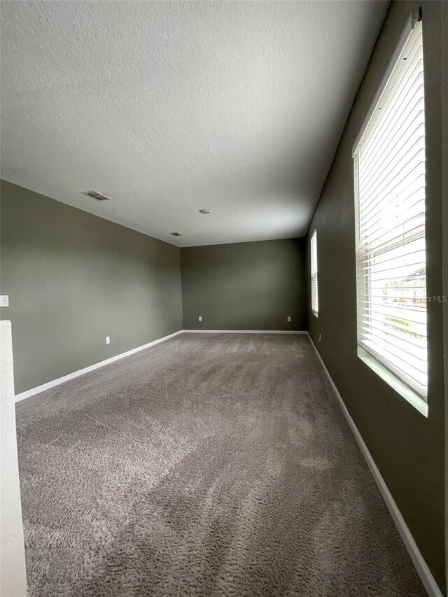 unfurnished room featuring a textured ceiling and carpet floors