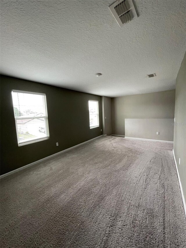 carpeted spare room featuring a textured ceiling