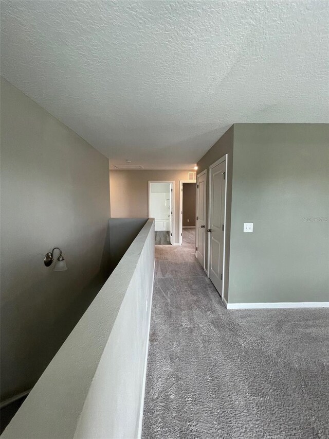 hall with carpet floors and a textured ceiling