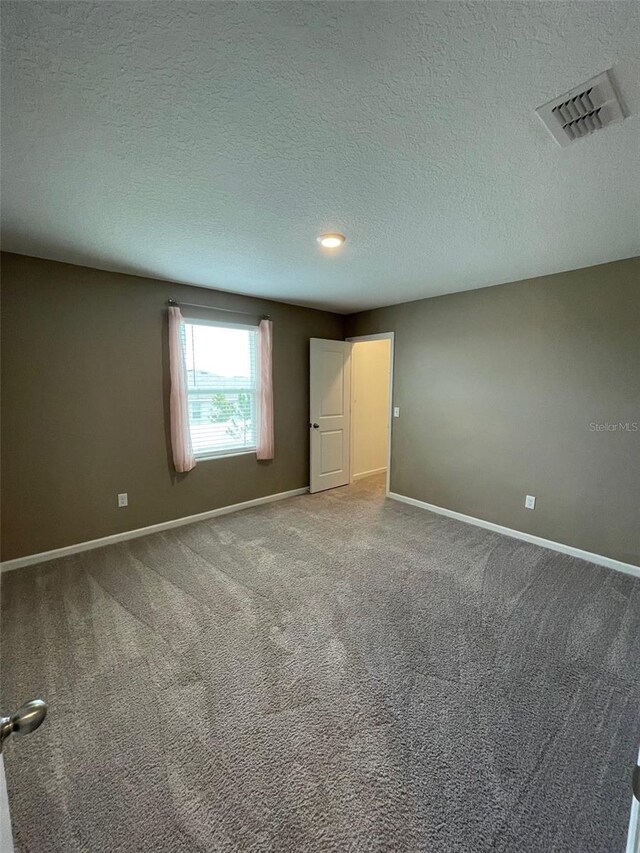 carpeted spare room featuring a textured ceiling