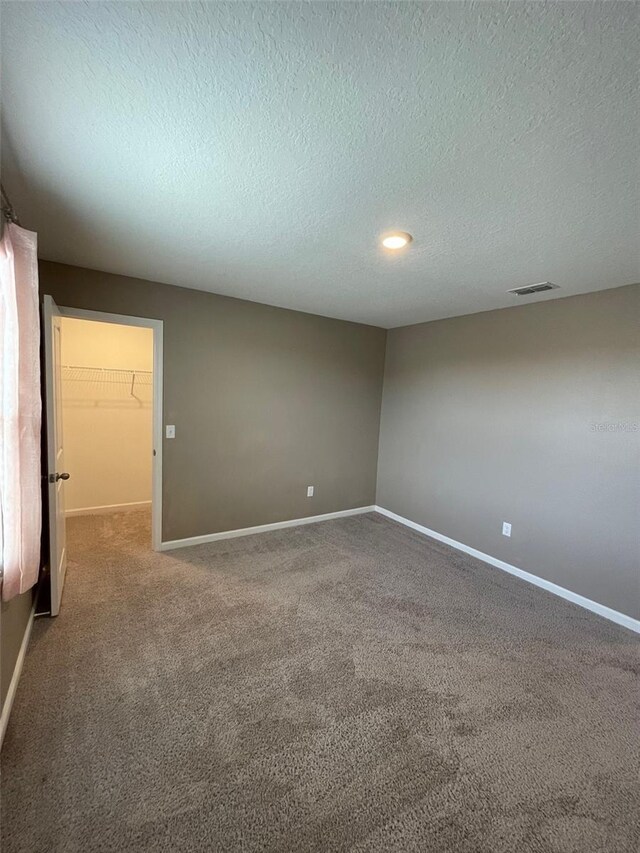 spare room featuring carpet flooring and a textured ceiling