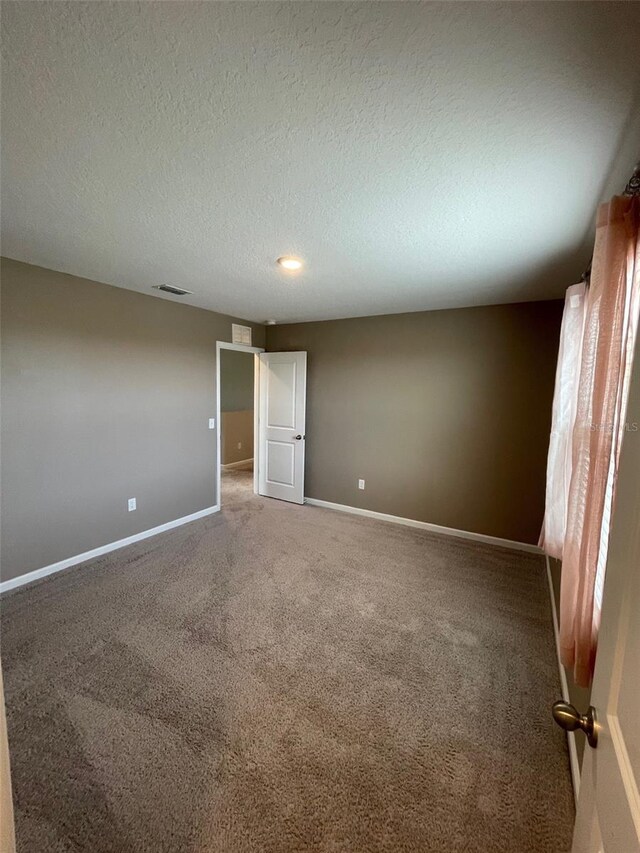 carpeted empty room with a textured ceiling