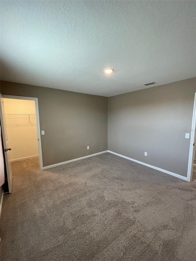 empty room featuring a textured ceiling and carpet floors