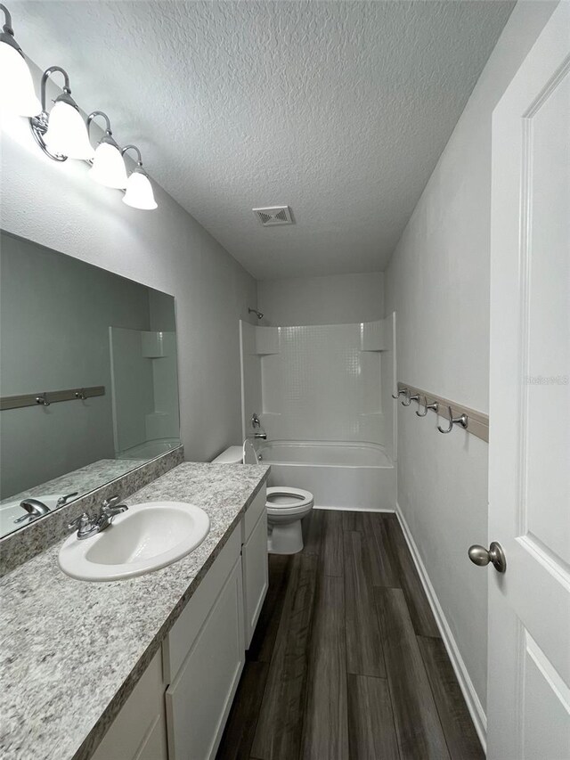 full bathroom featuring shower / bath combination, vanity, a textured ceiling, wood-type flooring, and toilet