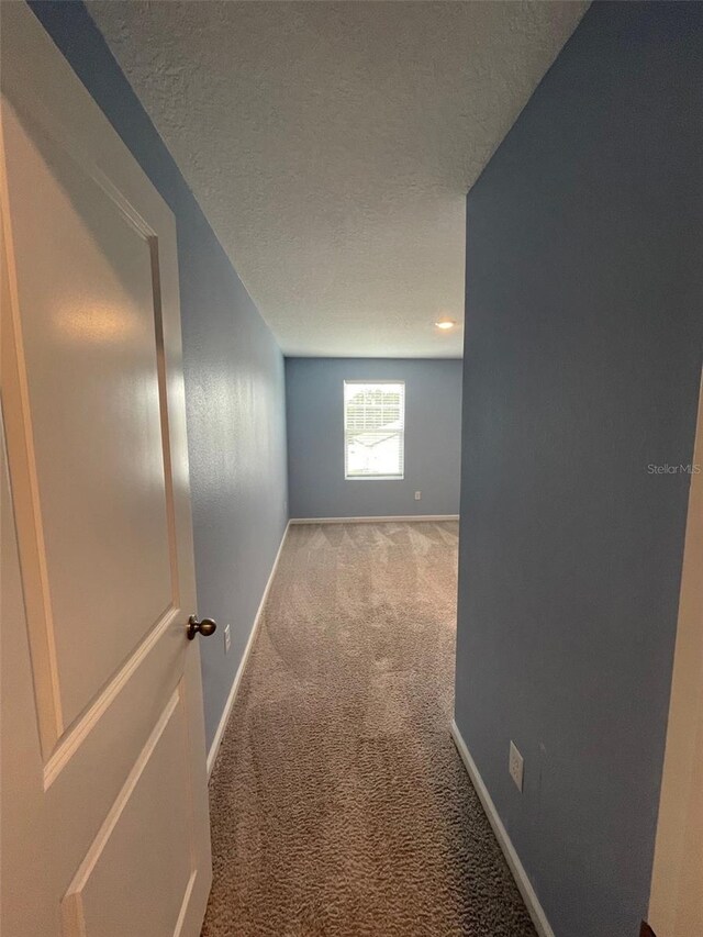 hall with carpet floors and a textured ceiling