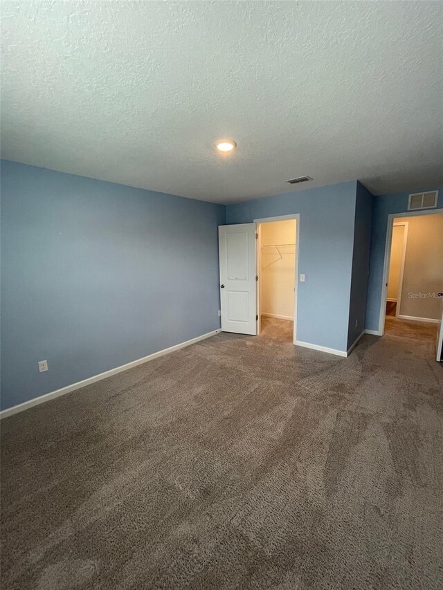 empty room featuring a textured ceiling and carpet floors