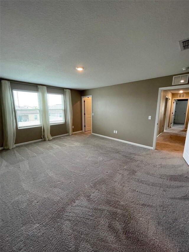 unfurnished room featuring light colored carpet and a textured ceiling