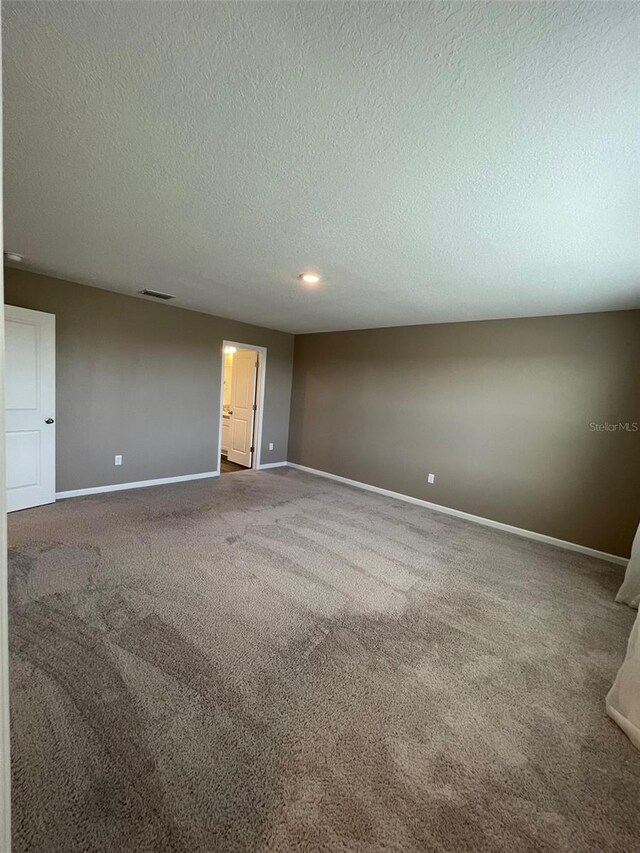 carpeted empty room with a textured ceiling