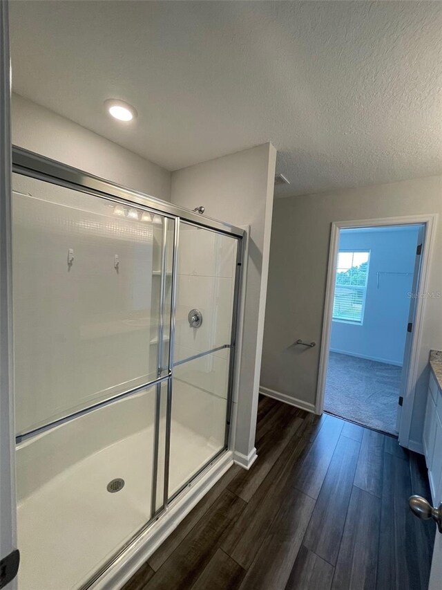 bathroom featuring vanity, hardwood / wood-style floors, a textured ceiling, and a shower with door