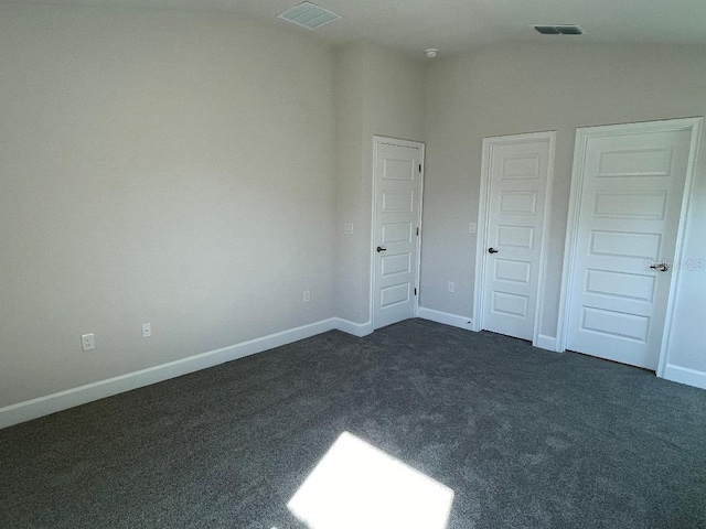 unfurnished bedroom featuring dark carpet and vaulted ceiling