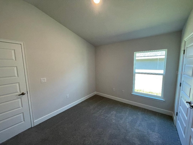 unfurnished bedroom with dark carpet and lofted ceiling