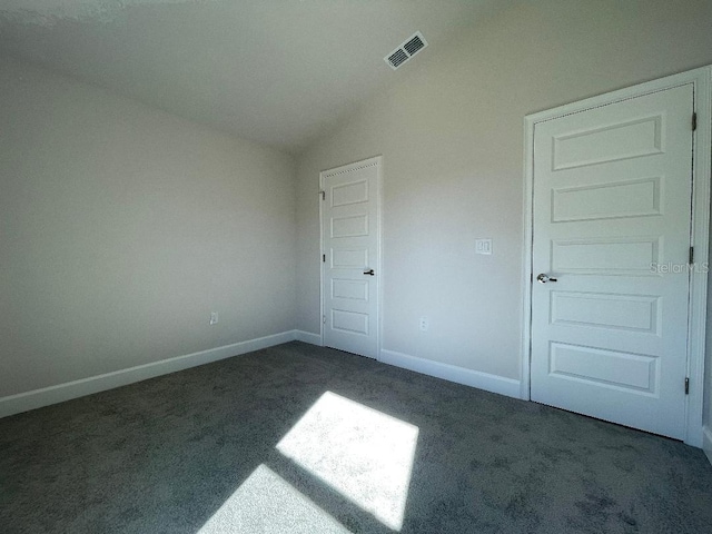 unfurnished bedroom featuring vaulted ceiling and dark colored carpet