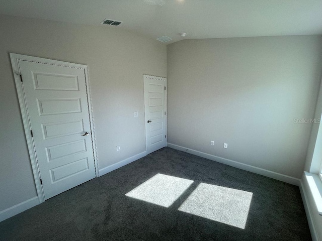 unfurnished bedroom with a closet, dark carpet, and vaulted ceiling