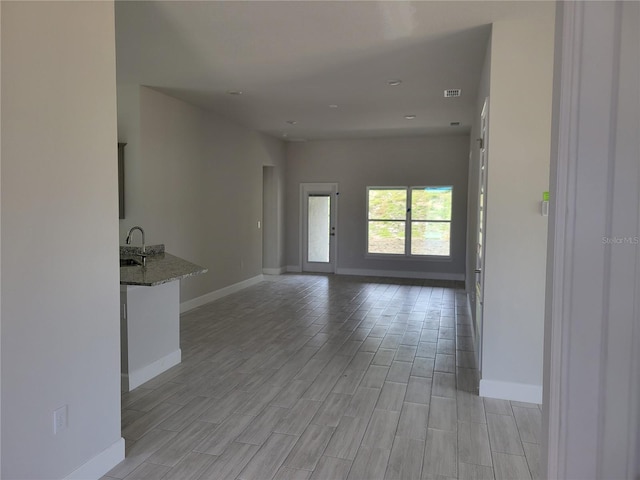 unfurnished living room featuring sink and light wood-type flooring