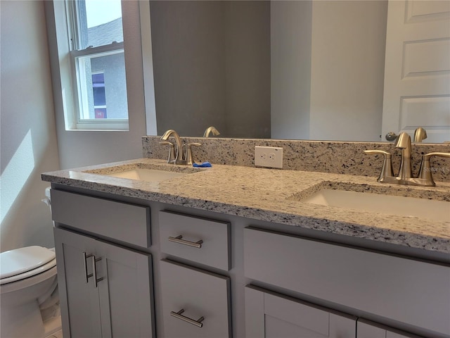 bathroom featuring a wealth of natural light, vanity, and toilet