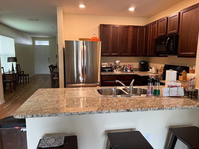 kitchen with dark hardwood / wood-style floors, kitchen peninsula, range, sink, and stainless steel refrigerator