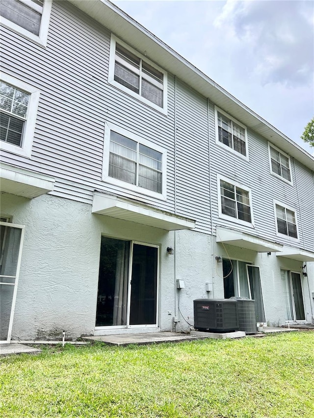 back of property featuring central AC unit and a yard