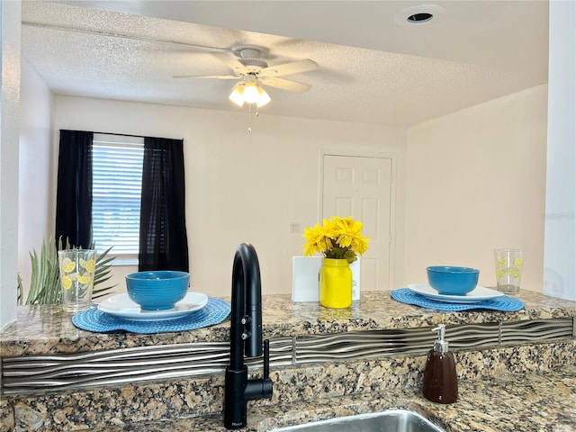 dining space featuring ceiling fan and a textured ceiling