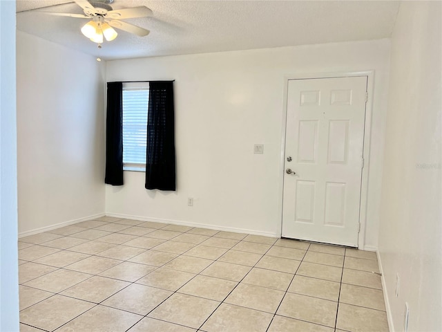 tiled spare room featuring a textured ceiling and ceiling fan