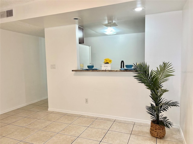 kitchen featuring light tile patterned flooring, stone countertops, and kitchen peninsula