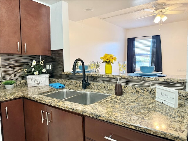 kitchen with tasteful backsplash, stone countertops, sink, and ceiling fan