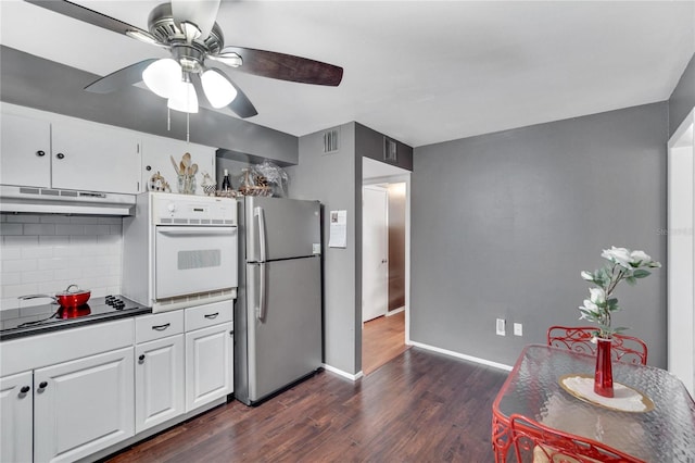 kitchen featuring dark hardwood / wood-style floors, backsplash, ceiling fan, stainless steel fridge, and white oven