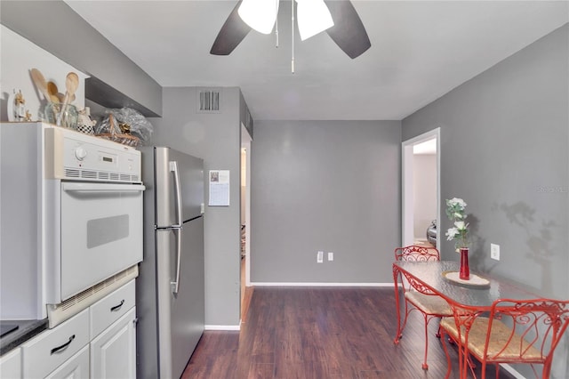 kitchen featuring dark hardwood / wood-style floors, ceiling fan, stainless steel fridge, and white cabinets