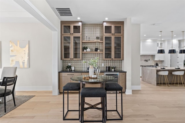 kitchen with pendant lighting, light hardwood / wood-style flooring, decorative backsplash, and a kitchen island