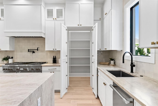 kitchen featuring sink, white cabinetry, tasteful backsplash, light hardwood / wood-style flooring, and appliances with stainless steel finishes