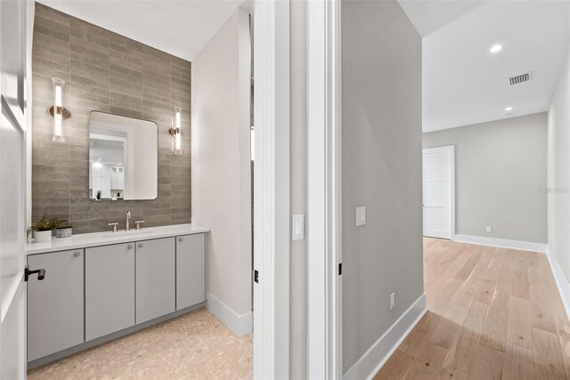 bathroom with hardwood / wood-style flooring, backsplash, and vanity