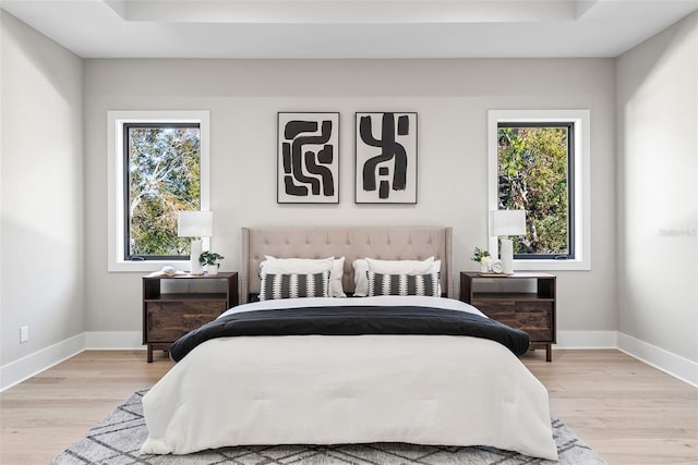 bedroom featuring a tray ceiling and light hardwood / wood-style flooring