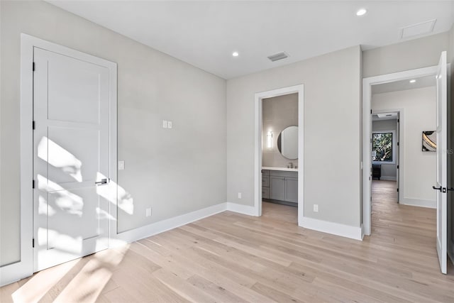 unfurnished bedroom featuring sink, light hardwood / wood-style flooring, and ensuite bath