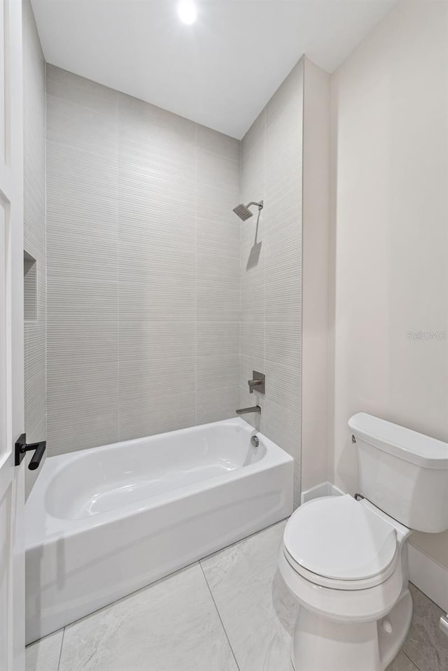 bathroom with tile patterned floors, tiled shower / bath combo, and toilet