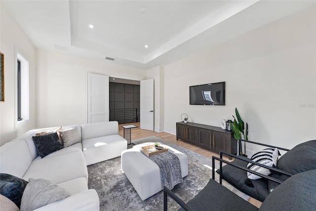 living room with a tray ceiling and hardwood / wood-style floors