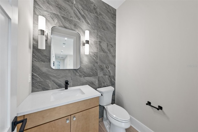 bathroom with tile walls, vanity, and toilet