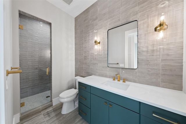 bathroom with toilet, decorative backsplash, tile walls, a shower with shower door, and vanity