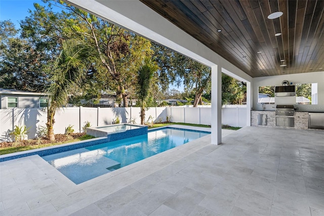 view of pool featuring an outdoor kitchen, area for grilling, an in ground hot tub, and a patio