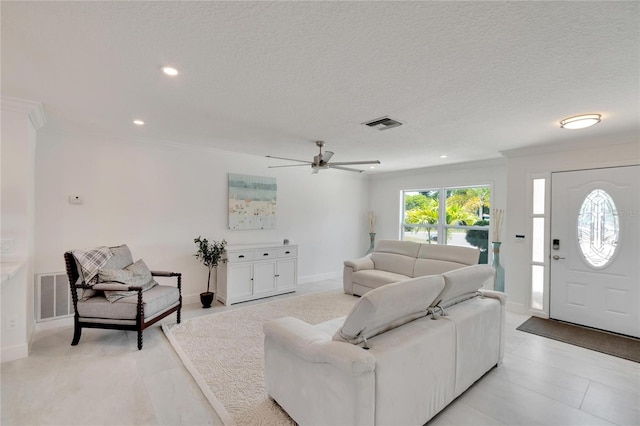 living room with ceiling fan, ornamental molding, and a textured ceiling