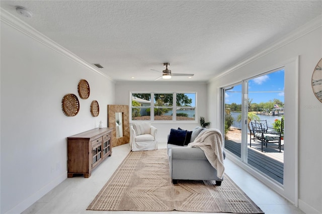 living room with ornamental molding, a textured ceiling, a water view, and a healthy amount of sunlight