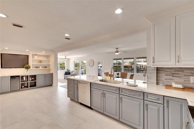 kitchen with gray cabinetry, sink, stainless steel dishwasher, ceiling fan, and built in features