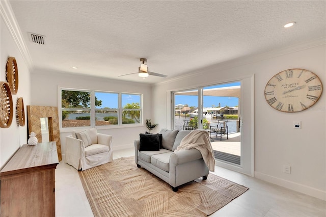 tiled living room featuring ceiling fan, a water view, a textured ceiling, and ornamental molding