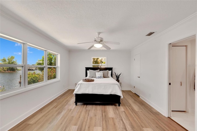 bedroom featuring a textured ceiling, ceiling fan, crown molding, a water view, and light hardwood / wood-style flooring