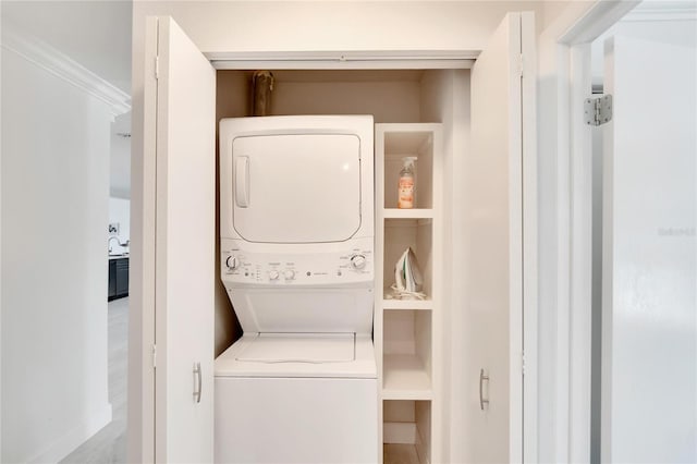 clothes washing area with stacked washer and dryer and ornamental molding