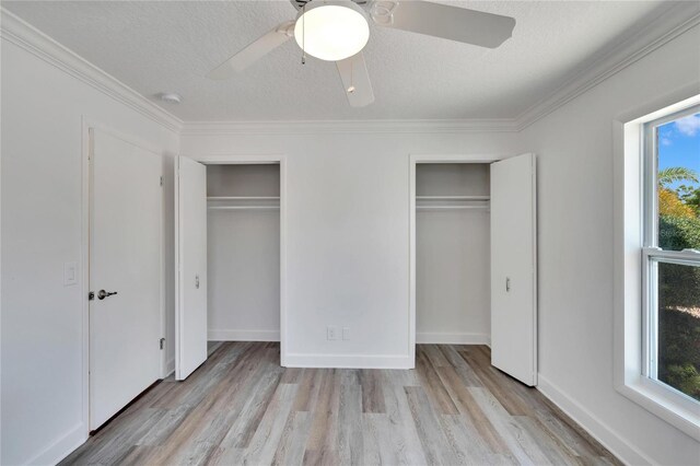 unfurnished bedroom featuring multiple closets, ceiling fan, a textured ceiling, and light wood-type flooring