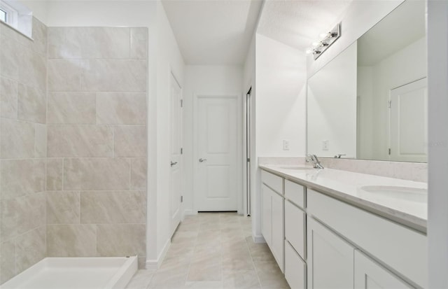 bathroom featuring tile patterned flooring, vanity, and a tile shower