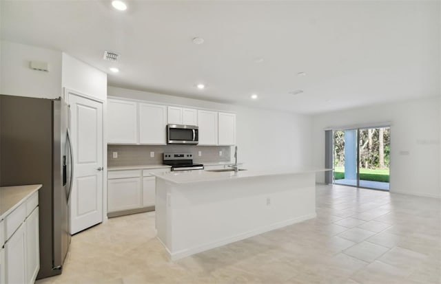 kitchen featuring decorative backsplash, white cabinetry, a kitchen island with sink, and appliances with stainless steel finishes